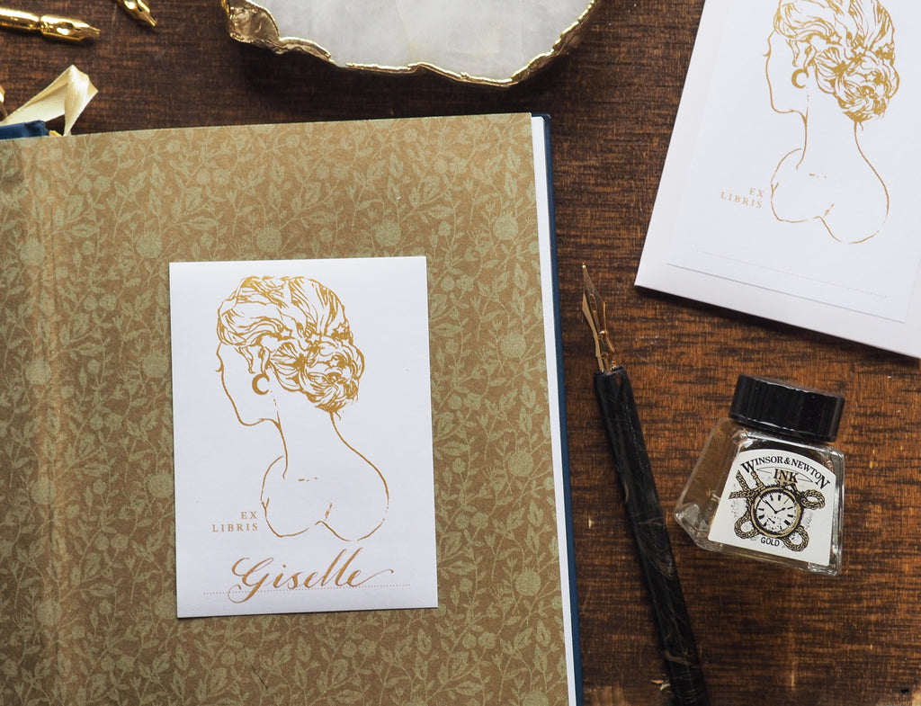 Bookplate with Giselle in calligraphy on gold and brown background with dip pens and ink