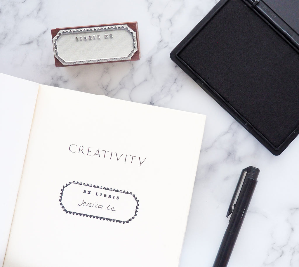 Ex libris blank stamp with pen, ink pad and open book with name written on inked design