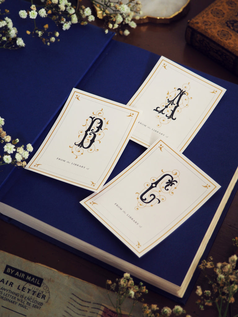 3 monogram initial bookplates of the letters A B and C placed on top of an open book