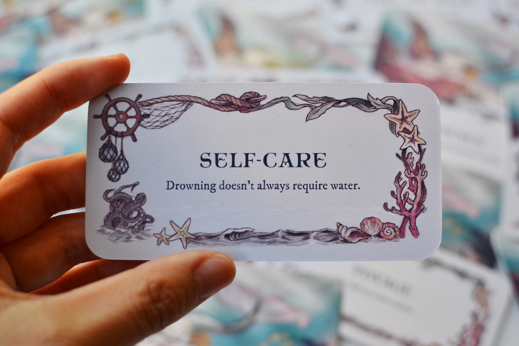 Hand holding 'Self Care' Sea Melodies mini inspiration card with unique corner illustration