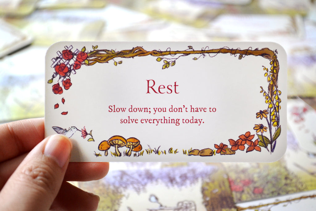 Hand holding 'Rest' Secret Garden mini inspiration card