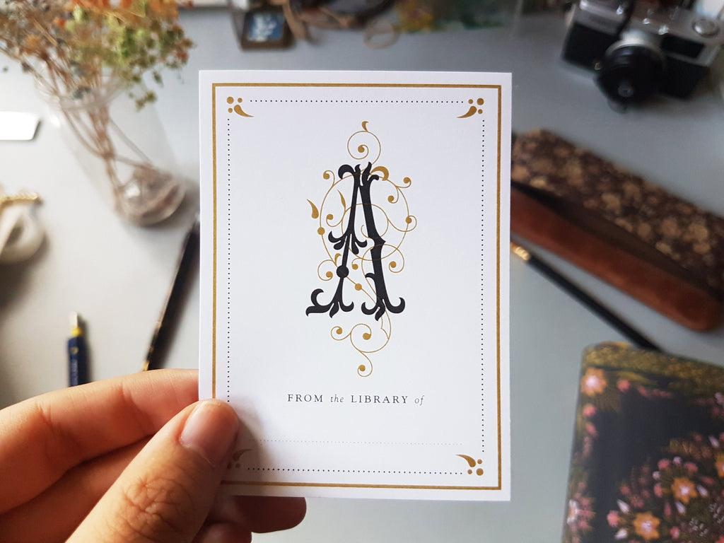 Hand holding a monogram initial bookplate sticker label of the letter A