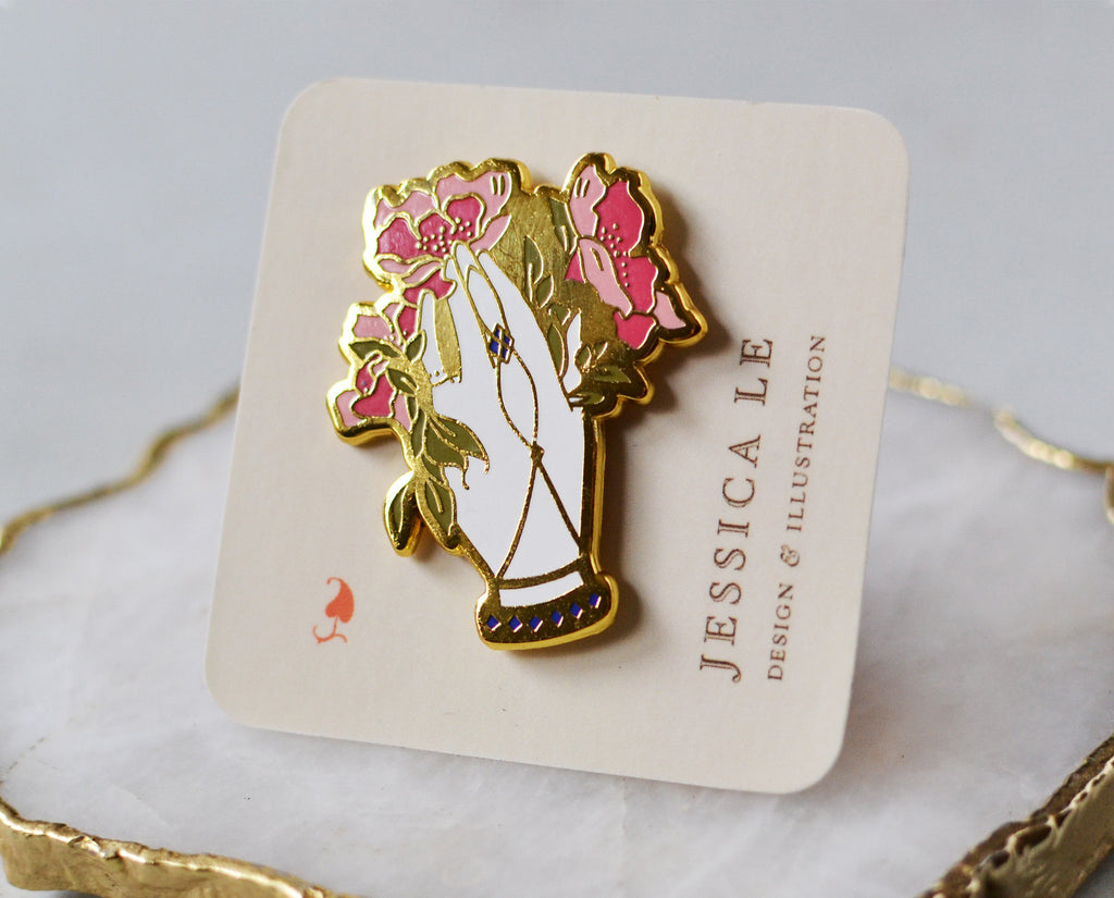 Victorial floral hand pin secured to backing card gleaming gold in the light