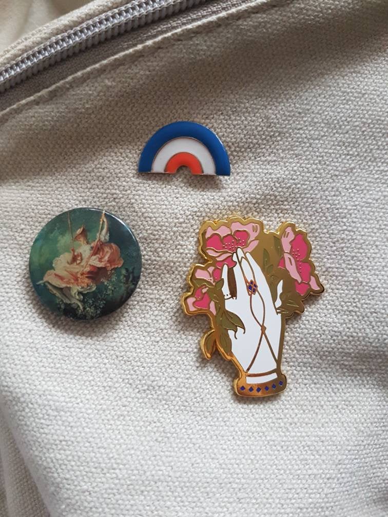 Victorian floral hand enamel pin secured to linen bag surrounded by other pins